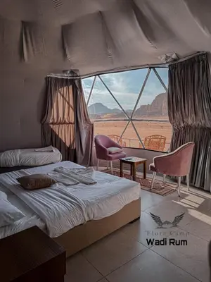 a bedroom with a bed and a view of the desert at Flora Camp Wadi Rum in Wadi Rum