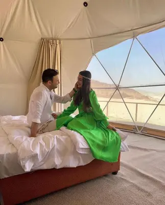 a man and woman sitting on a bed in a tent at RUM BUBBLES VIEW MARS lUXURY CAMP in Wadi Rum