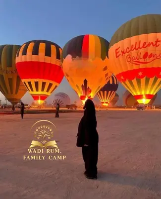 a person standing in front of a group of hot air balloons at RUM FAMiLY BUBBLES &BEDOUIN CAMP in Wadi Rum