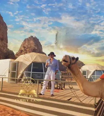 a man standing next to a camel on a boat at RUM FAMiLY BUBBLES &BEDOUIN CAMP in Wadi Rum