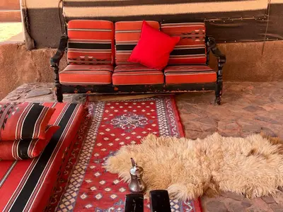 a living room with a couch and a red pillow at Wanderlust Jordan Camp in Wadi Rum