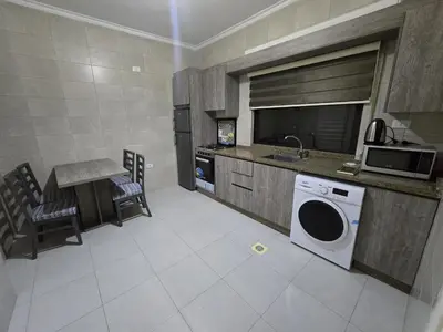 a kitchen with a sink and a washing machine at Gardens Complex in Amman