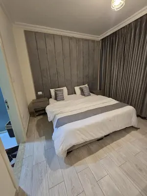a bedroom with a large bed with white sheets at Gardens Complex in Amman
