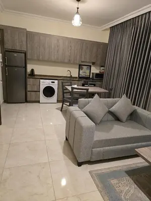 a living room with a couch and a kitchen at Gardens Complex in Amman