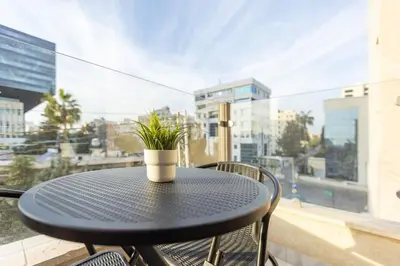a black table with a potted plant on a balcony at Shamsi Apartments 222 in Amman
