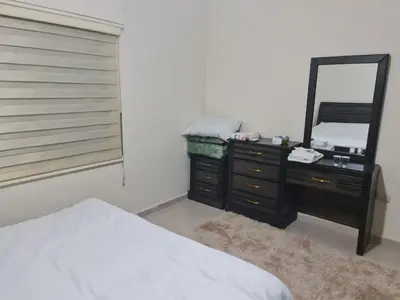 a bedroom with a dresser with a mirror and a bed at Samer Apartment in Amman