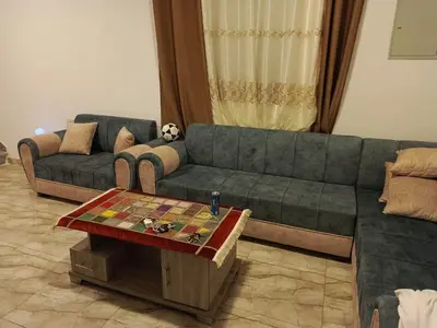 a living room with a green couch and a table at شاليه الاميرات in Sowayma