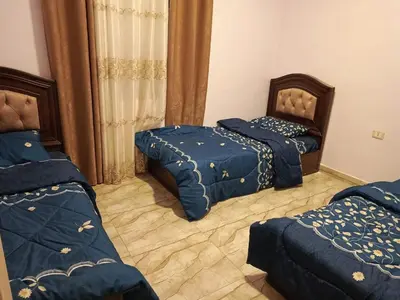 a bedroom with two beds with blue comforters at شاليه الاميرات in Sowayma
