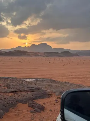 a car parked in the desert with the sunset at Luxury Desert Camp in Disah