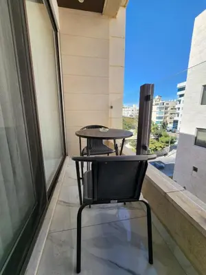 a table and a chair on a balcony at Shamsi Apartments 223 in Amman