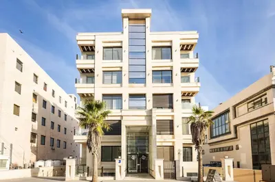 a white building with palm trees in front of it at Shamsi Apartments 330 in Amman
