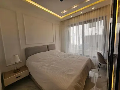 a white bedroom with a bed and a window at Shamsi Apartments 009 in Amman