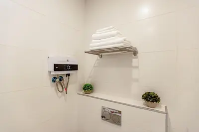 a white bathroom with white towels on a shelf at Shamsi Apartments 009 in Amman