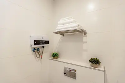 a white bathroom with a shelf with towels on it at Shamsi Apartments 437 in Amman