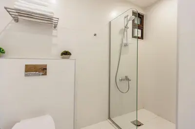 a white bathroom with a glass shower stall at Shamsi Apartments 437 in Amman