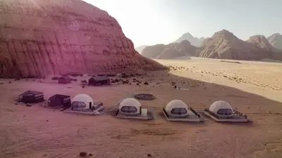 a group of tents in the desert near a mountain at Crown Luxury Camp in Wadi Rum