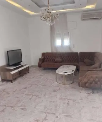a living room with a couch and a tv at kazbon House in Al Hāshimīyah