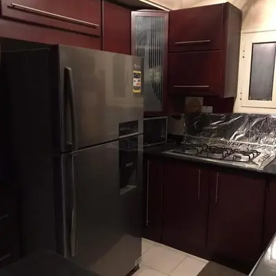a kitchen with a stainless steel refrigerator and wooden cabinets at birds House in Jerash