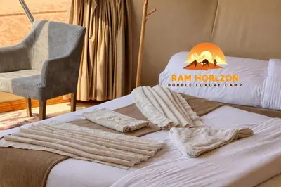 a bed with a chair and towels on it at RAM HORlZON LUXURY CAMP in Wadi Rum