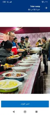 a buffet line with people waiting for their plates of food at Al-Faris Camp in Disah