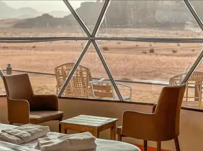 a room with chairs and tables and a view of the desert at Nova Luxury Camp in Wadi Rum