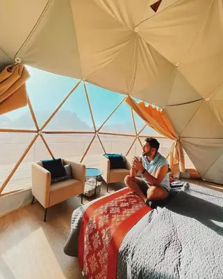 a man sitting on a bed in a tent at Nova Luxury Camp in Wadi Rum