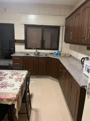 a kitchen with wooden cabinets and a table and a sink at University Castle in Amman