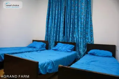 two beds in a room with blue curtains at Sky Blue Farm in Umm Jawzah