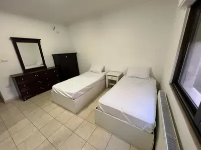 two beds in a room with a mirror and a dresser at On the street 3 Room in Amman