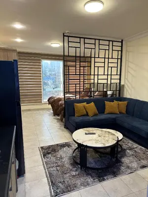 a living room with a blue couch and a table at gardens studio استوديو الجاردنز 401 in Amman