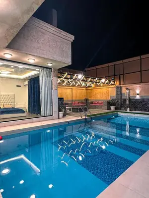 a large swimming pool in a hotel at night at Firuza Farm Villa Vip in Al Rama