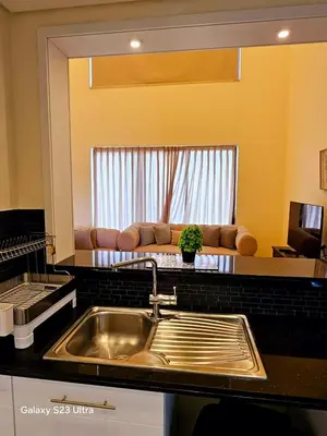 a kitchen with a sink and a couch in a living room at C33 Samarah Resort LOFT apartment in Sowayma