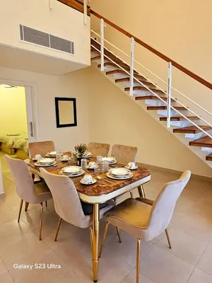 a dining room table with chairs and a staircase at C33 Samarah Resort LOFT apartment in Sowayma