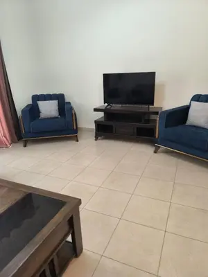a living room with two blue chairs and a flat screen tv at C04 Samarah Resort One Bedroom apartment in Sowayma