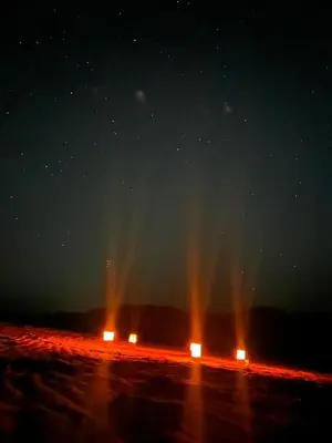 two lights in the middle of a field at night at Wadi Rum Kenan Camp in Wadi Rum