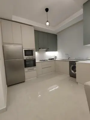 a kitchen with white cabinets and stainless steel appliances at Newly Built apartment Deir Ghbar in Amman