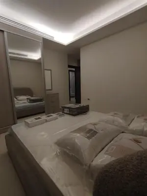 a large bed in a room with a large mirror at Newly Built apartment Deir Ghbar in Amman