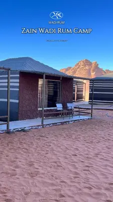 a building with two benches in front of it at Zain Wadi Rum Camp in Wadi Rum