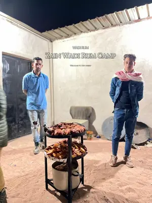 two men standing in a room with a table of food at Zain Wadi Rum Camp in Wadi Rum