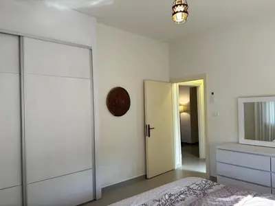 a white bedroom with a bed and a mirror at Modern 2BR in Trendy Jabal AlWebdeh with View in Amman