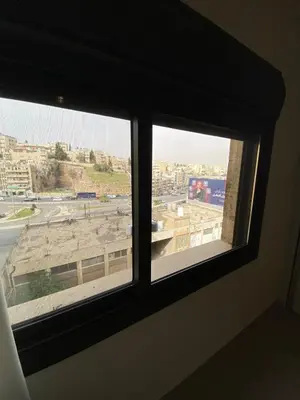 two windows in a room with a view of a building at Modern 2BR in Trendy Jabal AlWebdeh with View in Amman