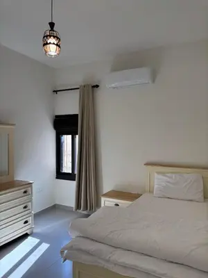 a bedroom with a bed and a dresser and a window at Modern 2BR in Trendy Jabal AlWebdeh with View in Amman