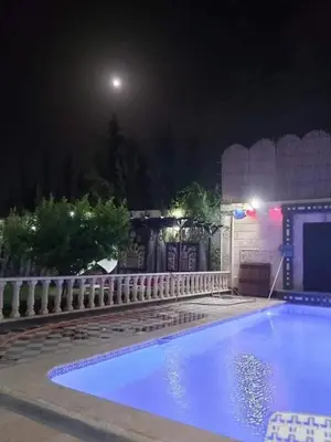 a swimming pool at night with the moon in the background at الزئبق فارم in Maḩaţţat al Ḩafīf