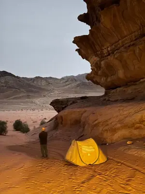 a man standing next to a tent in the desert at Wadi Rum Sunrise Guesthouse in Wadi Rum