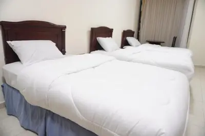 two beds in a room with white sheets and pillows at النخيل للشقق الفندقية ALnakheel hotel apartment in Aqaba