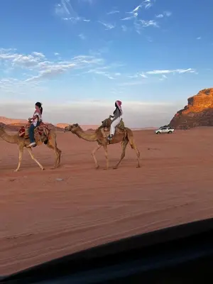 two people riding on the backs of camels in the desert at Gakleen luxury camp in Aqaba