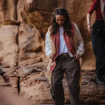 a woman wearing a vest and a scarf walking down a path at Wadi rum Mahmoud tours in Wadi Rum