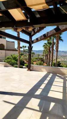 a patio with awning and palm trees in the background at منتجع وفيلا تل الرمان in Ar Rummān