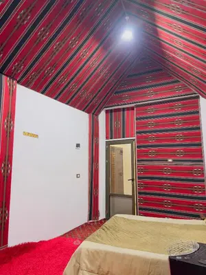 a room with a bed in a room with red walls at Bedouin House in Jurf ad Darāwīsh