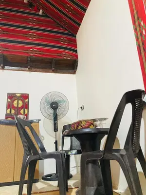 a room with two chairs and a table and a fan at Bedouin House in Jurf ad Darāwīsh